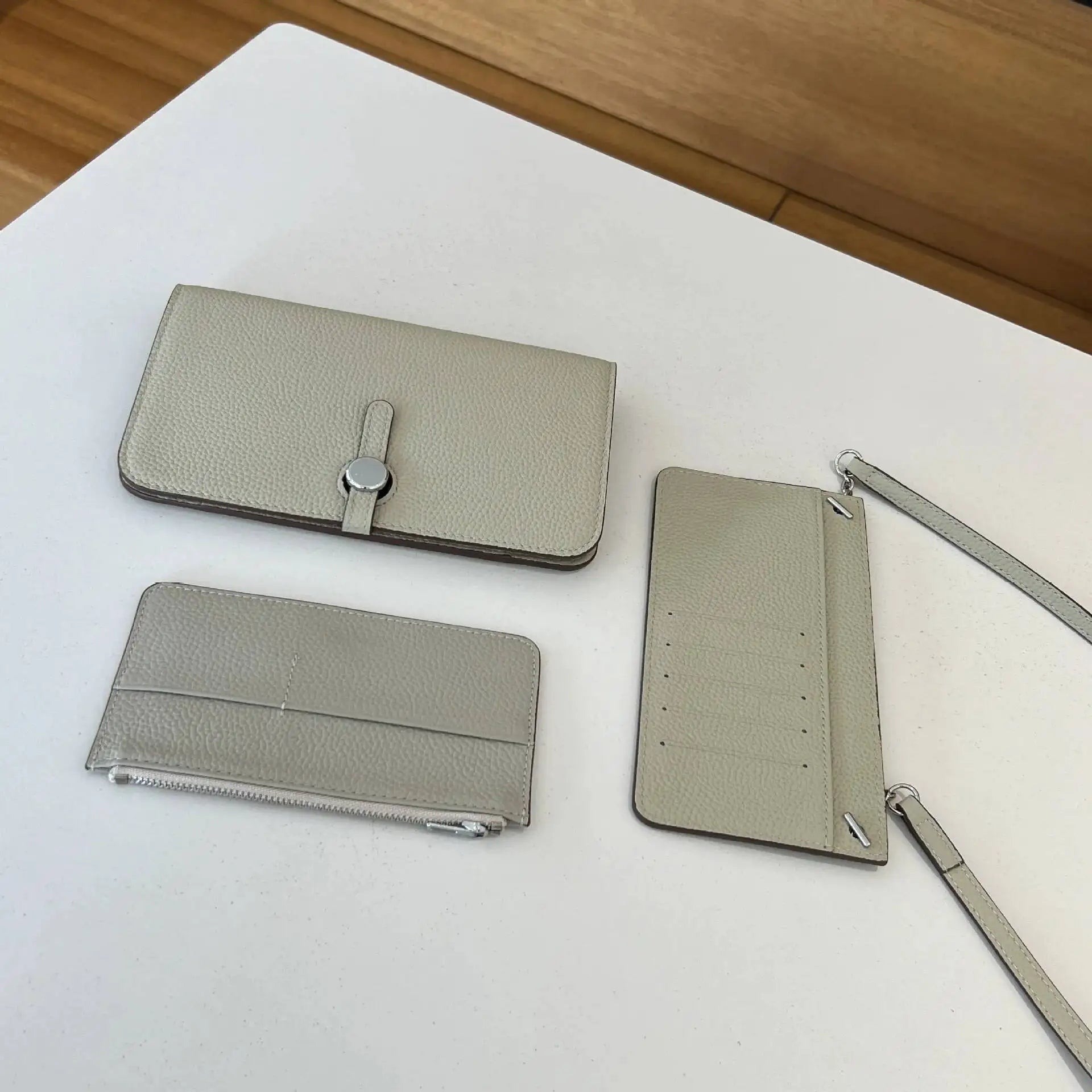 Set of beige leather accessories including a wallet, cardholder, and phone case on a white surface.