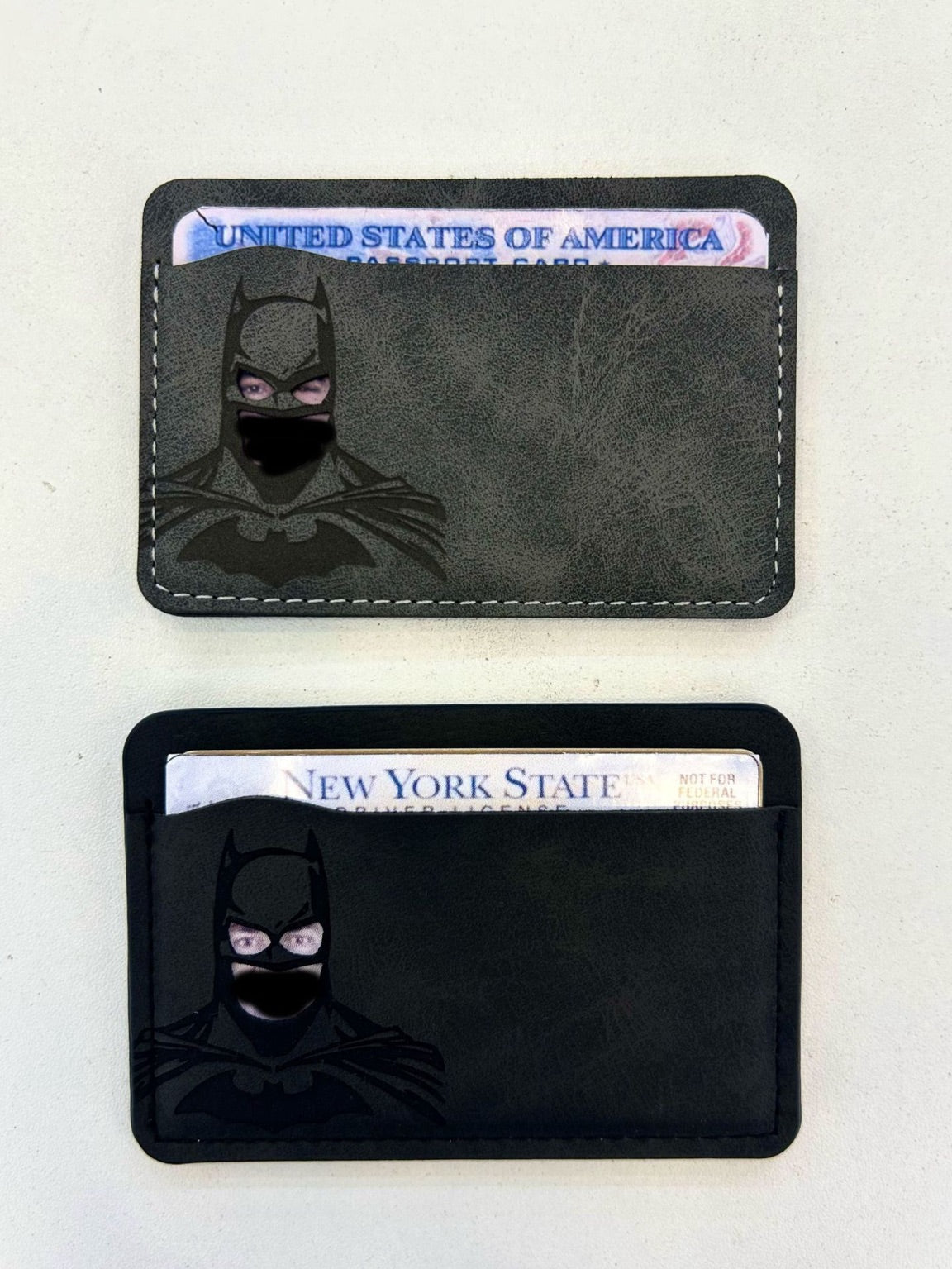 Two black card holders with a masked design on a white background